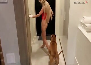 Blonde dressed in red is letting dog put the tip of its dick inside